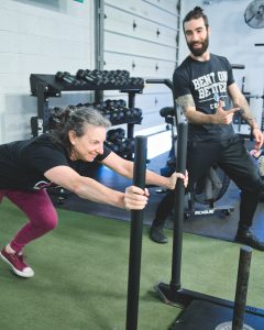 a trainer helping a member get through her workout in a gym