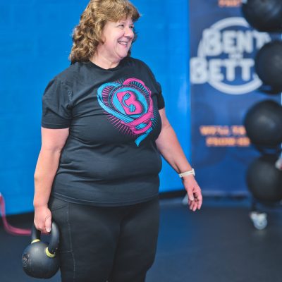 a woman carrying one 35 lbs. kettlebell in a gym