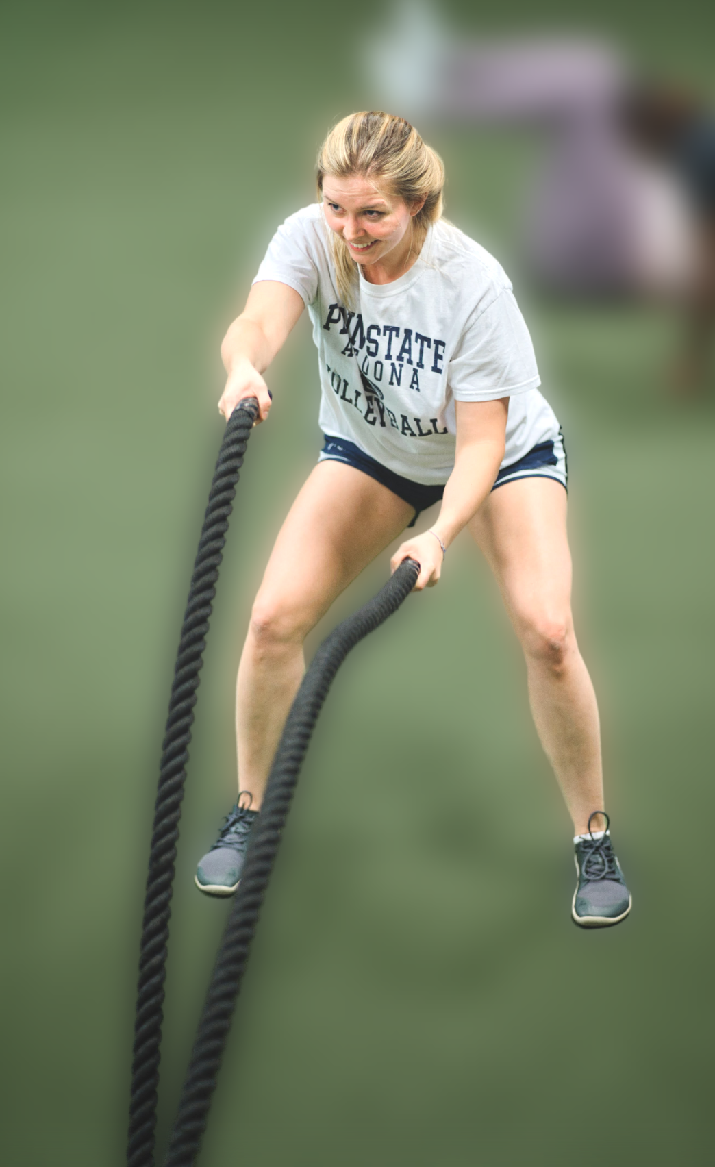 a woman using a battle rope in a gym
